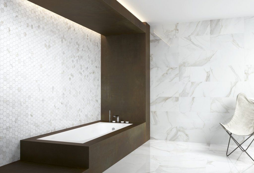 Baño moderno con paredes de mármol blanco, detalles de madera oscura y bañera incorporada.