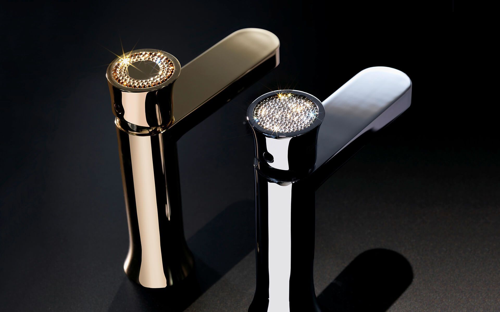 Dos grifos de baño dorados y plateados con tapas enjoyadas sobre un fondo negro.