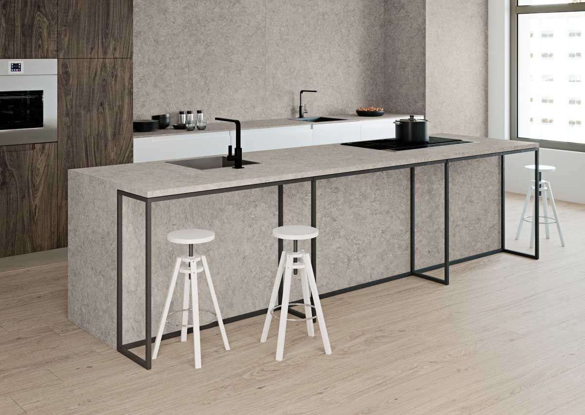 Cocina moderna con superficies de piedra gris, detalles de metal negro y taburetes blancos.