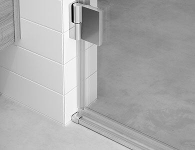 Primer plano de una bisagra de puerta de ducha fijada a una pared de azulejos blancos.