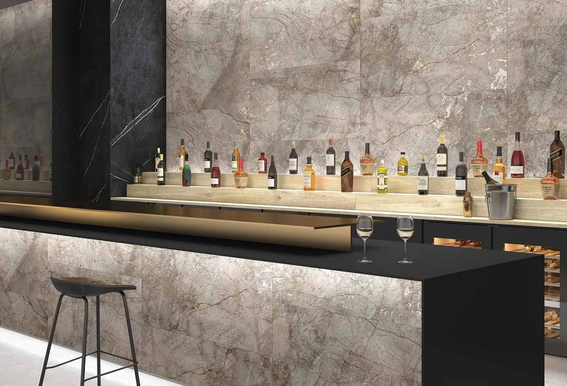 Barra con botellas en un estante. Un mostrador negro con taburetes, copas de vino y un toque metálico.