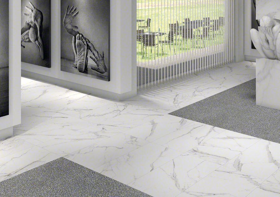 Piso de mármol blanco con detalles en gris, arte enmarcado y una escultura cerca de una ventana con vista al exterior.