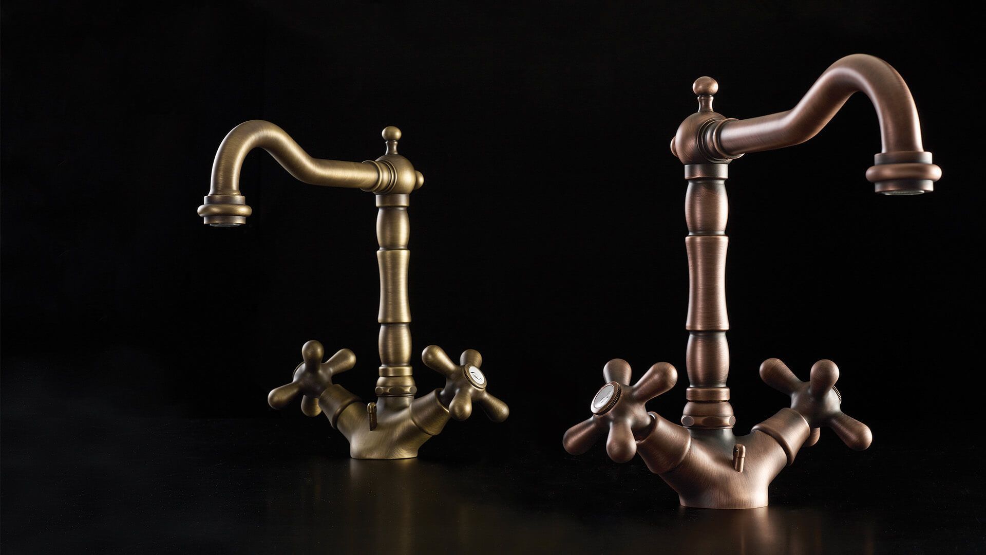 Dos grifos de estilo vintage, uno de latón y otro de cobre, descansan sobre una superficie negra.