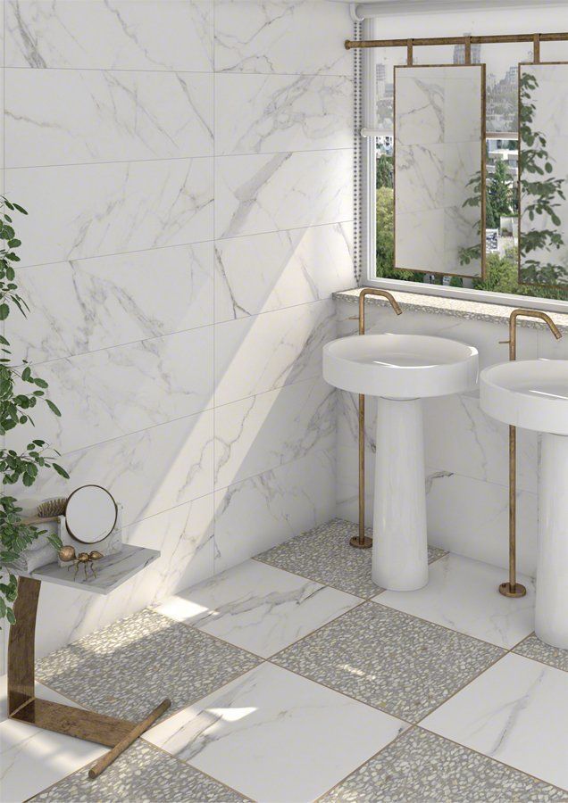 Un baño moderno con paredes y pisos de mármol, dos lavabos con pedestal y una ventana con espejos.