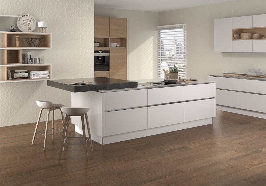 Cocina moderna blanca con isla, suelo de madera y taburetes.