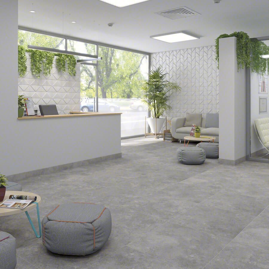 Moderna sala de espera con mostrador de recepción, sofá y plantas, con grandes ventanales a una calle arbolada.