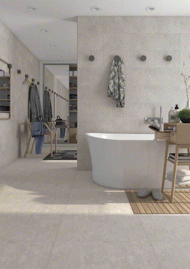 Baño con bañera independiente blanca, azulejos de color claro y detalles de madera.