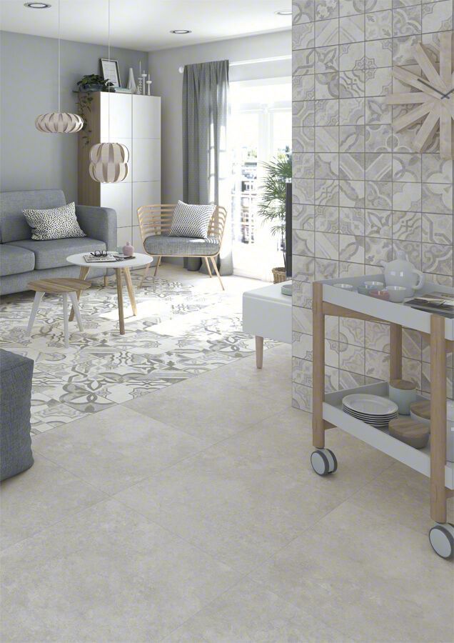 Sala de estar con sofá gris, alfombra estampada, paredes de colores claros y pared con acento de azulejos decorativos.