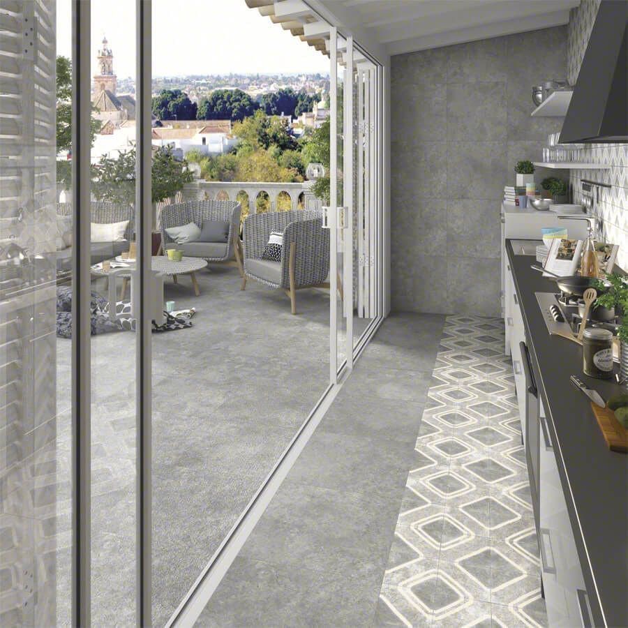 La cocina abierta conduce a un balcón con muebles de patio y vista a la ciudad; combinación de colores gris y blanco.