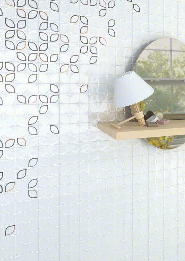 Pared de azulejos blancos con estampado floral, pequeño estante que sostiene una lámpara, espejo con vista al exterior.