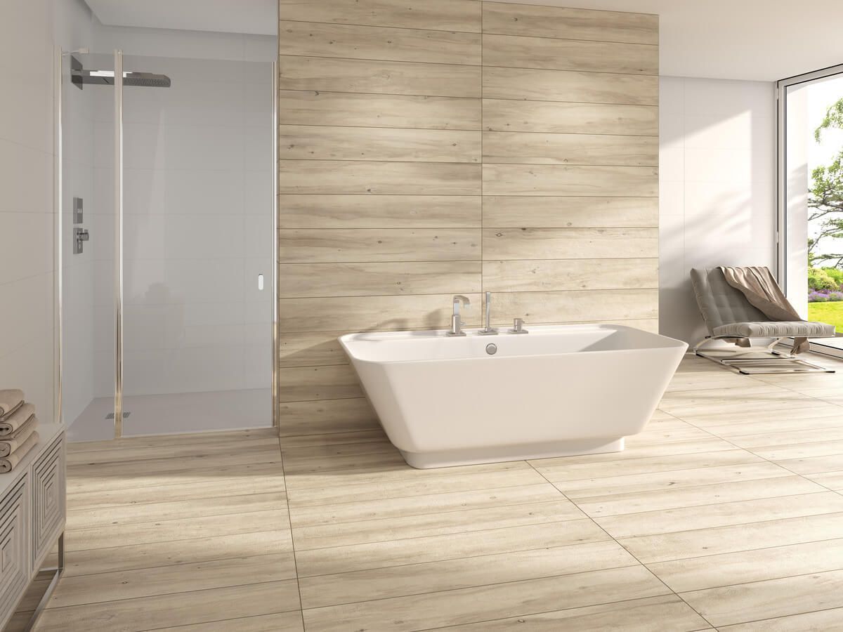 Baño moderno con bañera, ducha y ventana. Azulejos imitación madera clara, grifería blanca y silla.