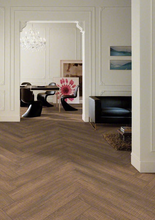 El piso de espiga de madera conduce a una habitación luminosa y elegante con paredes blancas, arte y muebles.