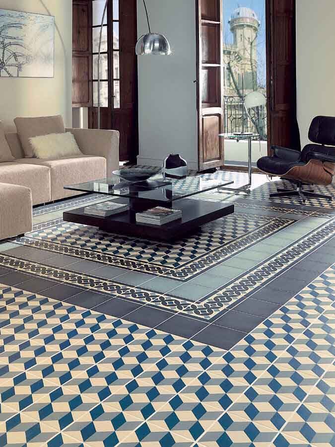 Sala de estar con piso de baldosas estampadas, ventanas de madera oscura, sofá beige y mesa de café con tapa de vidrio.