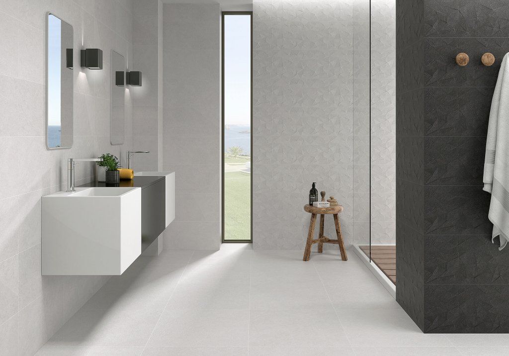 Baño moderno con paredes blancas y grises, ducha y lavabos flotantes.