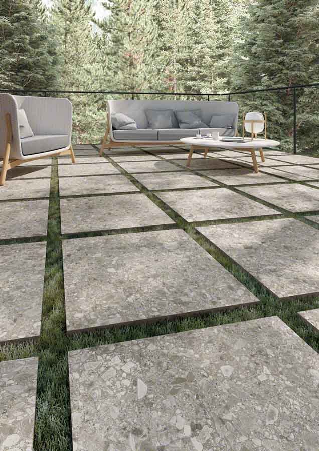 Patio con baldosas cuadradas de piedra y césped entre ellas. Zona de estar al aire libre con vistas al bosque.