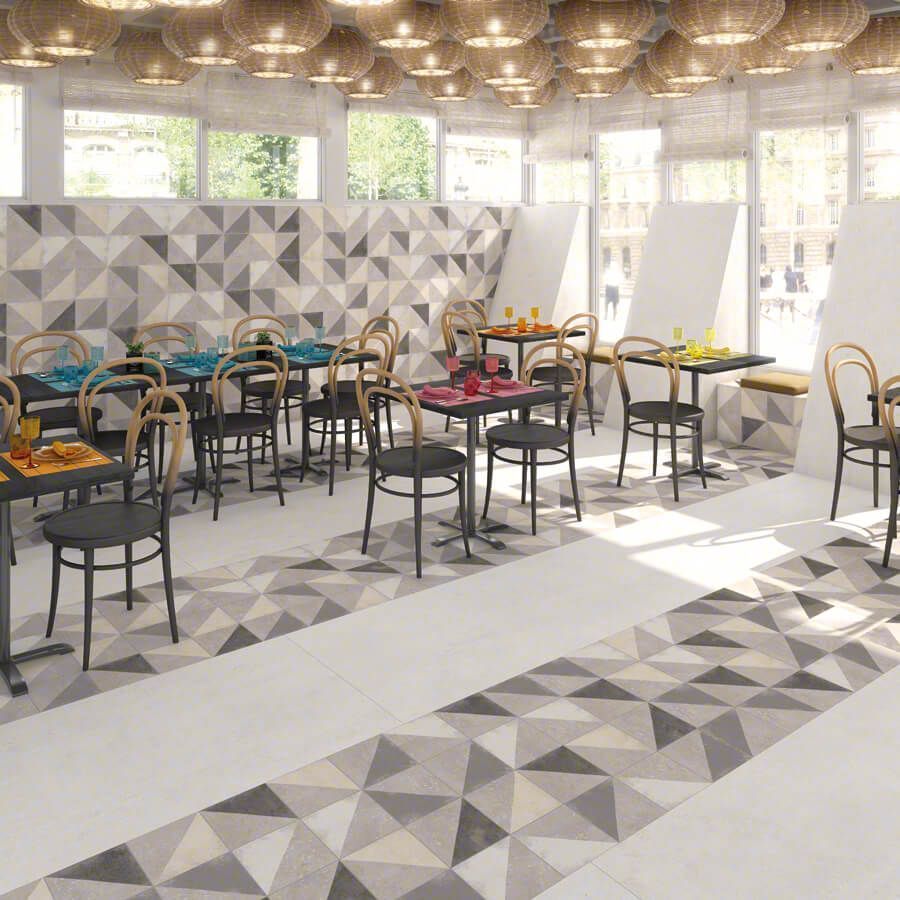 Interior de restaurante con mesas y sillas; azulejos de pared y suelo con motivos geométricos; luces de techo.