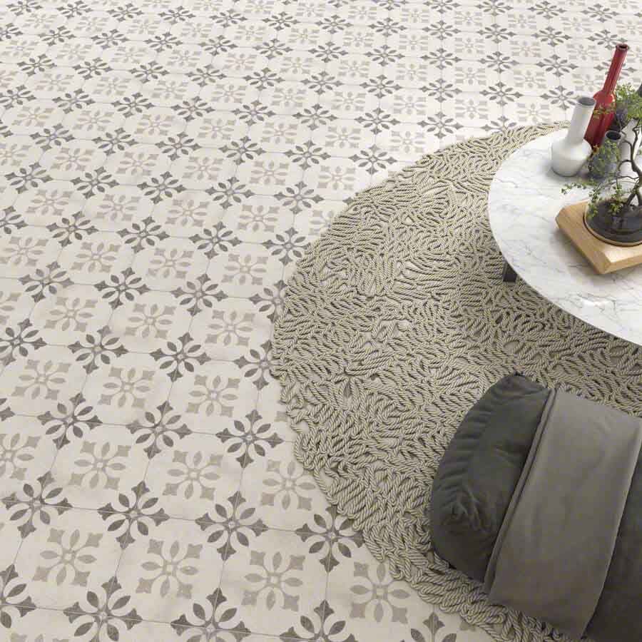 Piso con baldosas con estampado floral, alfombra redonda y mesa de café con decoración.