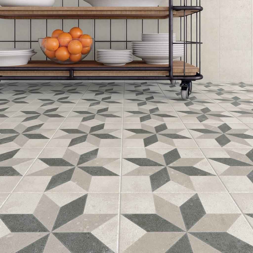 Suelo de cocina con azulejos con estampado de estrellas en gris, gris claro y beige. Estantería de madera con vajilla y fruta.