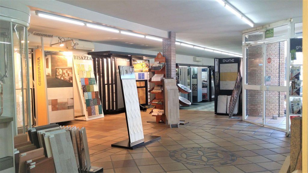 Interior de una tienda de azulejos con diversos expositores y muestras. La sala de exposición está iluminada con luz fluorescente.