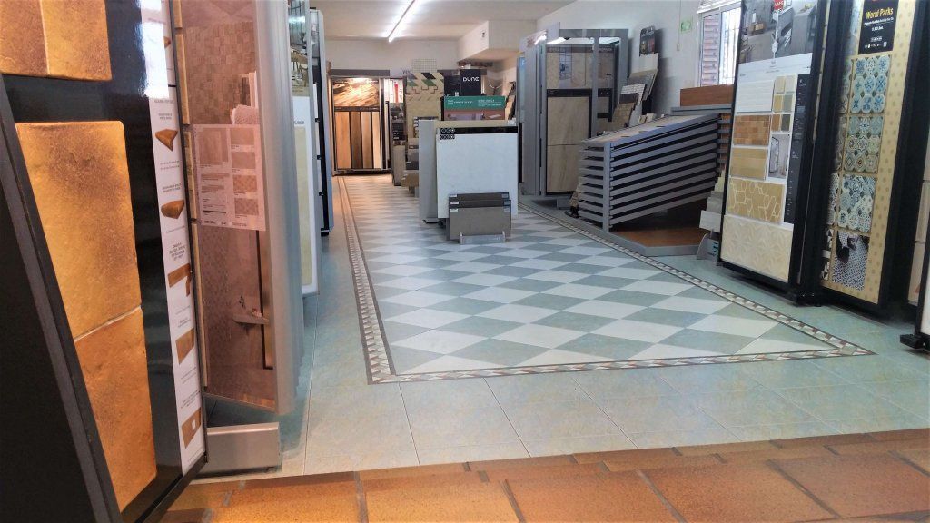 Una sala de exposición de azulejos con suelo a cuadros, exhibiciones de azulejos y varios electrodomésticos.