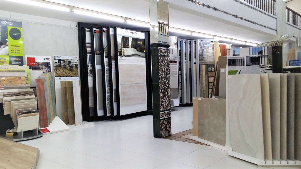 Interior de una sala de exposición de azulejos, con muestras de azulejos exhibidas en paneles verticales y exhibiciones en el piso.