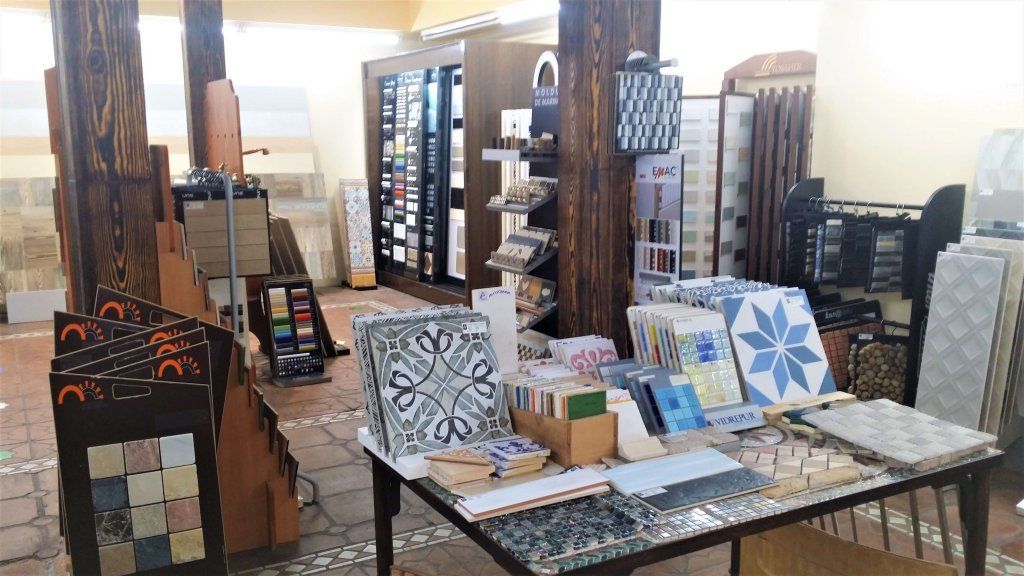Interior de una tienda de azulejos con mesas de exhibición que muestran varios patrones y muestras de azulejos.