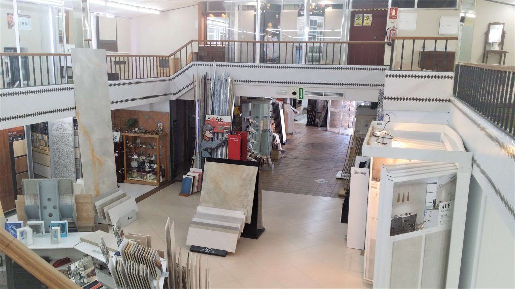Interior de sala de exposición de azulejos de varios niveles con exhibidores de azulejos y un balcón.