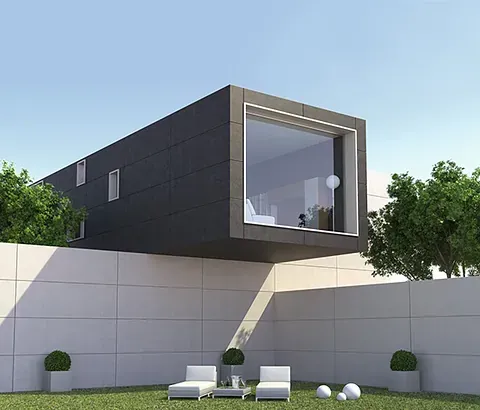 Casa moderna con grandes ventanales que dan a un patio con paredes de hormigón, sillas y vegetación.