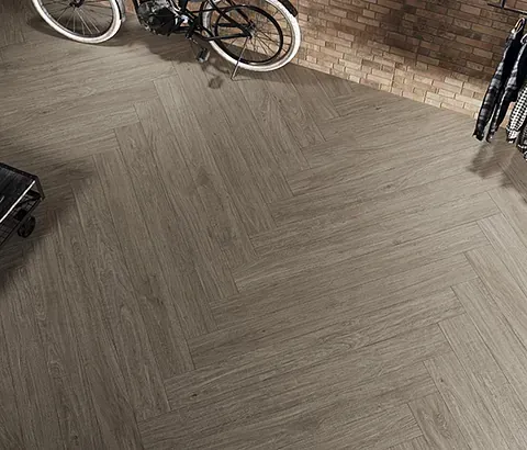 Suelo de madera en espiga en una habitación con bicicleta y pared de ladrillo.