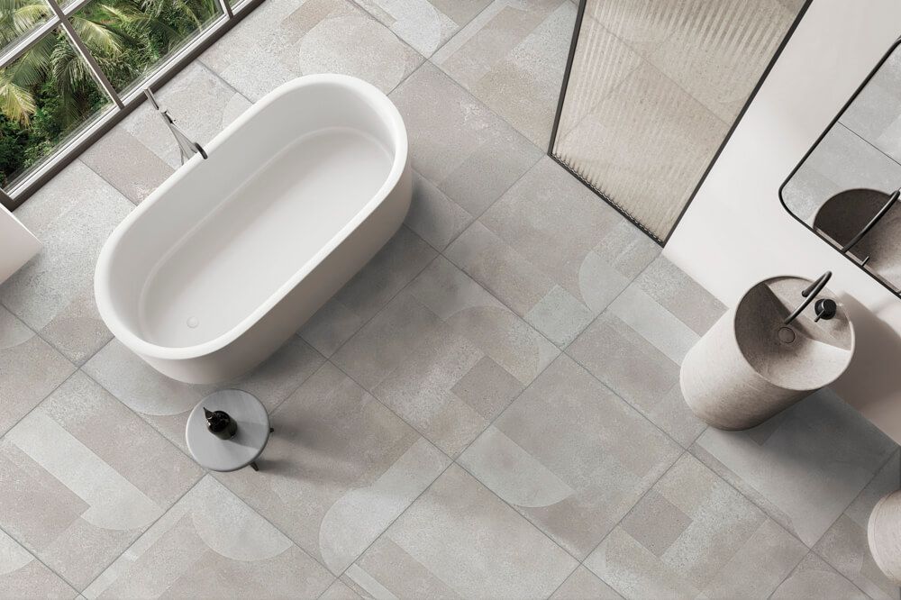 Baño moderno con bañera ovalada, suelo estampado y lavabo alto.