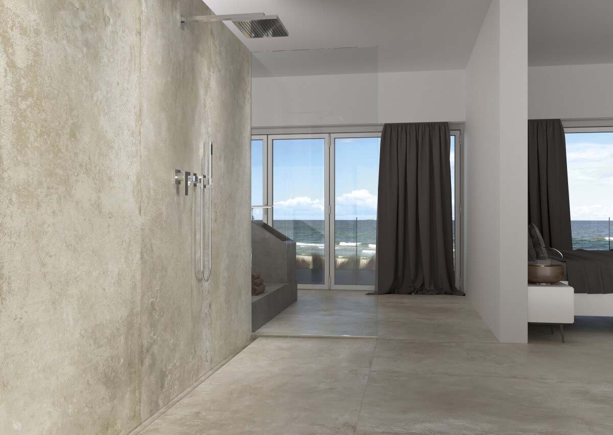 Baño moderno con paredes texturizadas de color beige, ducha con mampara de cristal y vista al mar.