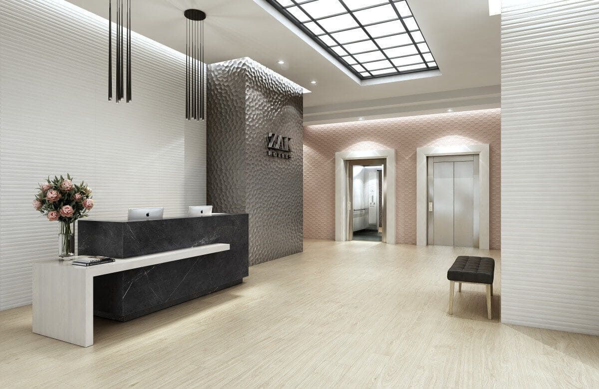 Lobby moderno con mostrador de recepción de mármol negro, paredes texturizadas y ascensores.