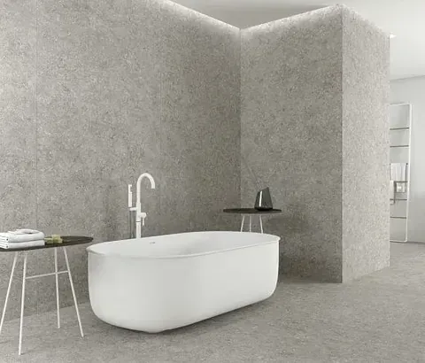Baño moderno con bañera blanca, paredes gris claro y decoración minimalista.