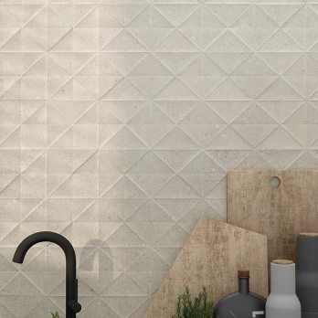 Salpicadero de azulejos texturizados de color beige con grifo negro y tablas de cortar de madera.