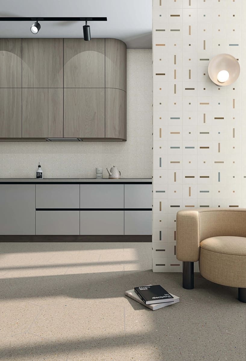 Cocina moderna y sala de estar con gabinetes de madera clara, encimeras grises y pared estampada.