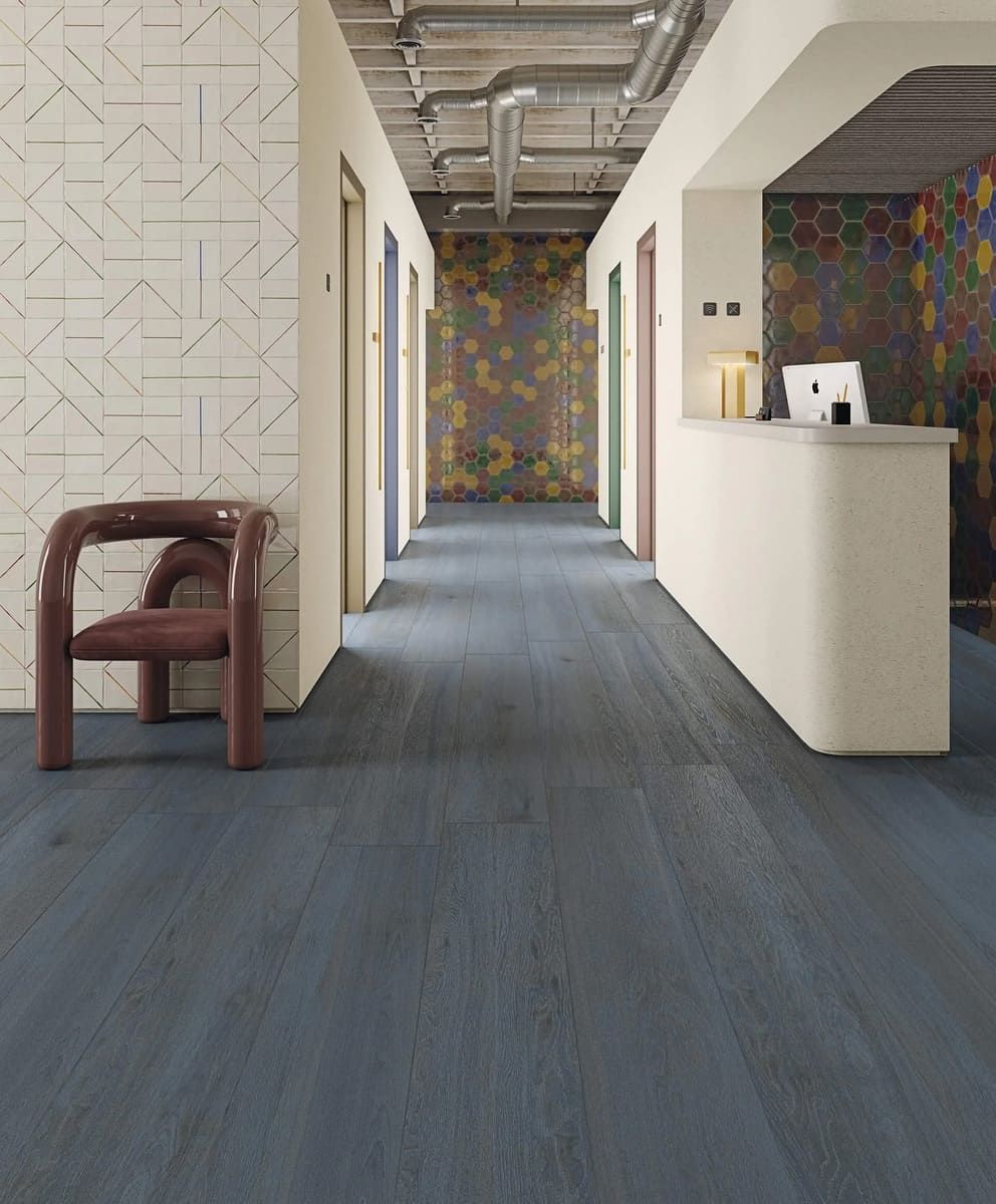 Pasillo con suelo de madera azul, varias puertas de colores y un mostrador de recepción.