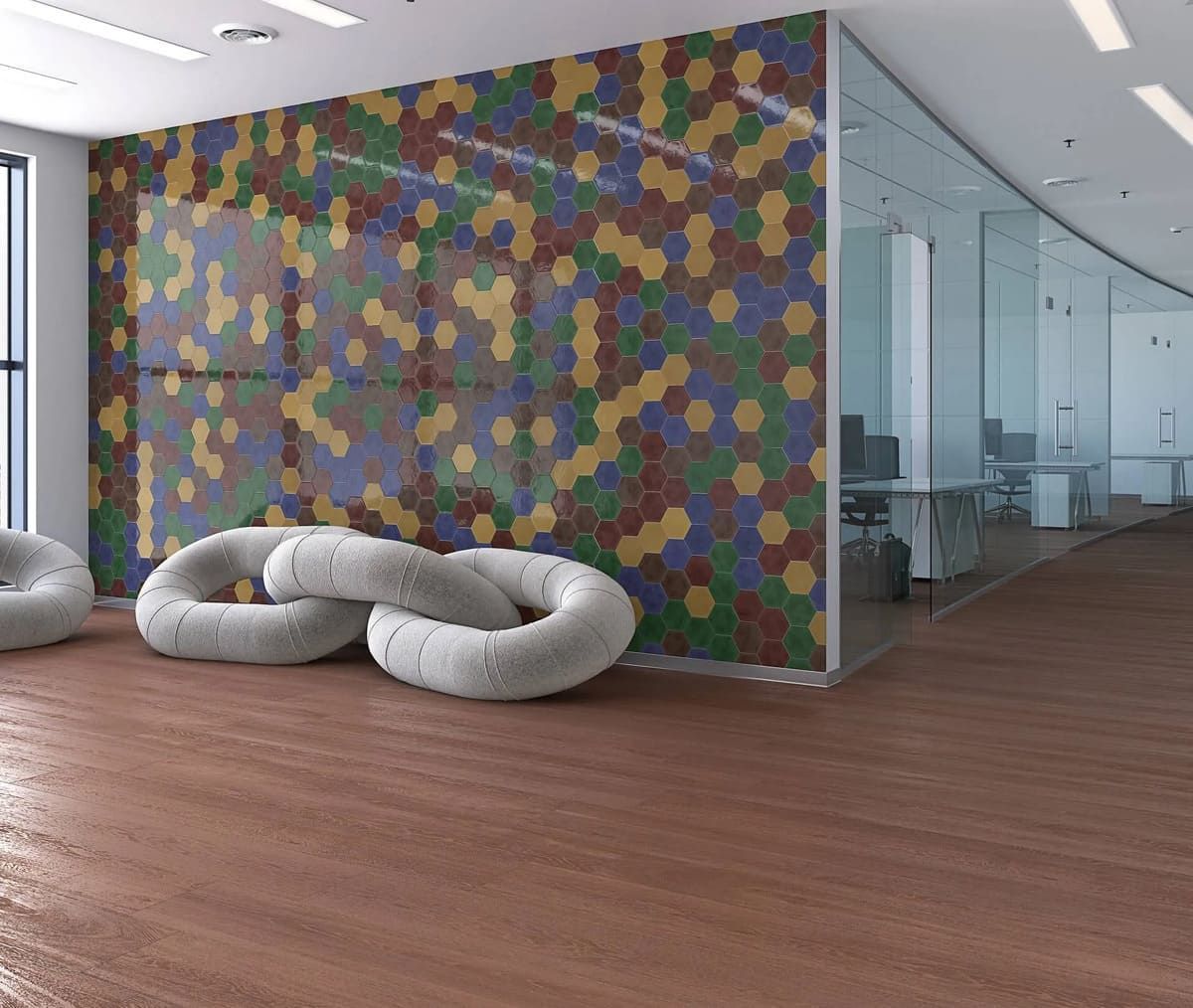 Interior de oficina moderno con piso de madera marrón, pared hexagonal colorida, paredes de vidrio y asientos acolchados redondos.