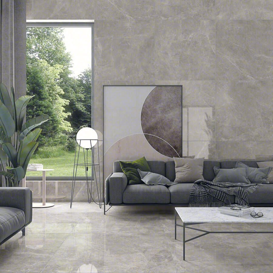 Moderna sala de estar con piso y paredes de baldosas grises, un sofá gris y una gran ventana con vista a los árboles.