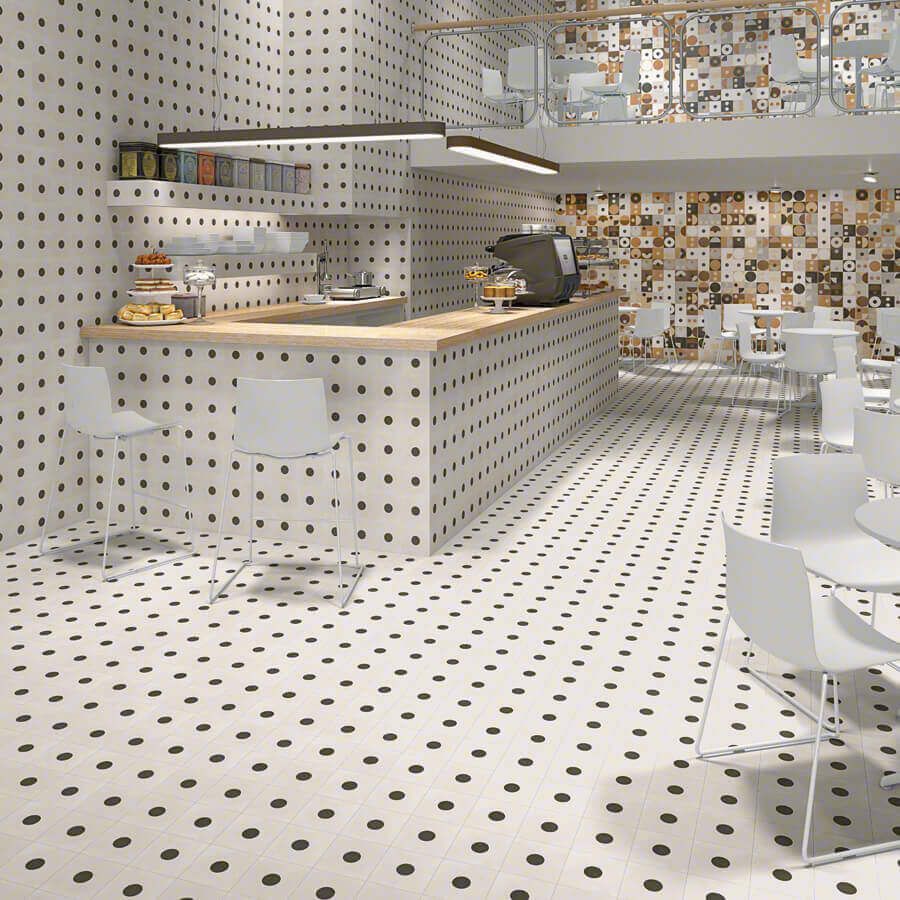 Interior de cafetería con azulejos de lunares blancos, barra y sillas blancas.