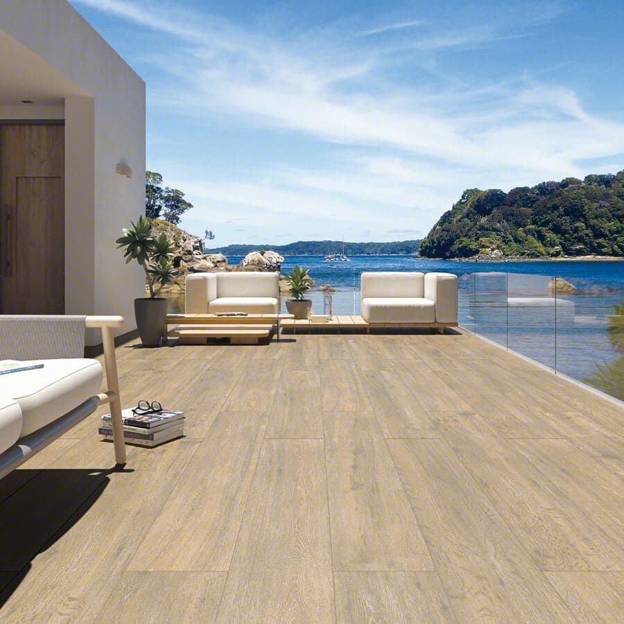 Patio de madera con muebles blancos con vista panorámica al mar.