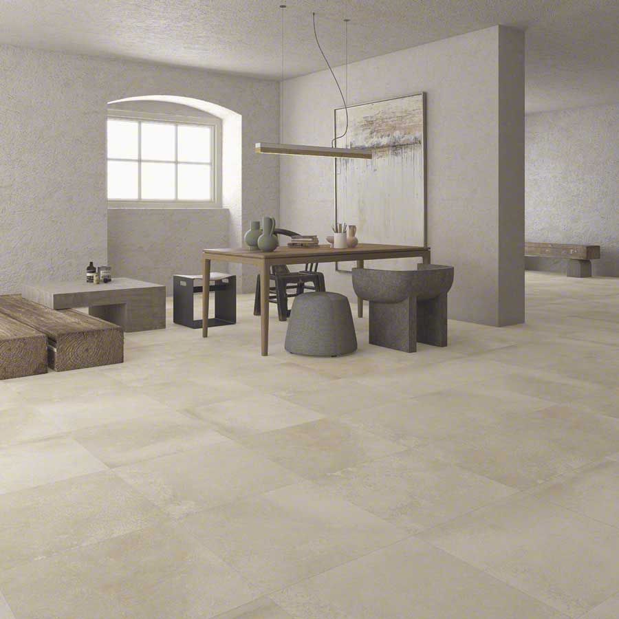 Habitación espaciosa con suelos de tonos claros, mesa de comedor y asientos. Paredes neutras, ventanal e iluminación moderna.