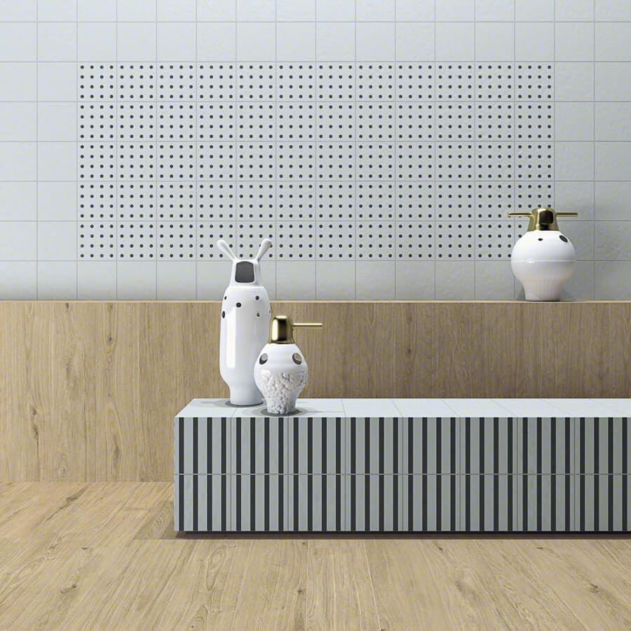 Viñeta de baño: mueble de rayas blancas y grises, revestimiento de madera, pared de tablero perforado, objetos decorativos y suelo de madera clara.