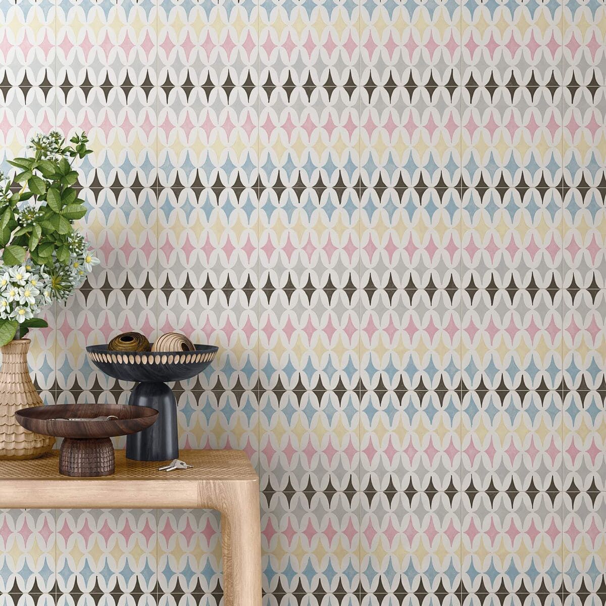 Pared con dibujos de rombos en colores pastel, al lado de una mesa con decoración.