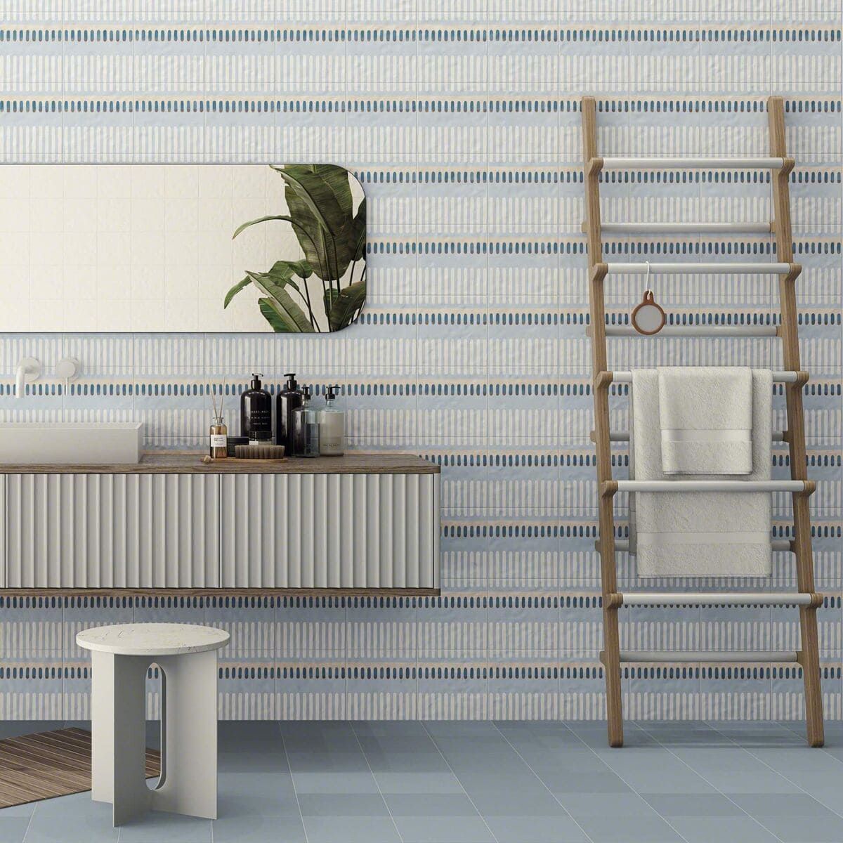 Baño con azulejos de rayas azules y blancas, tocador, espejo, escalera y taburete.