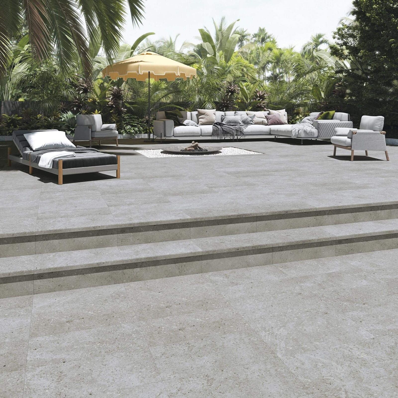 Patio al aire libre con escalones de concreto, muebles y follaje tropical.