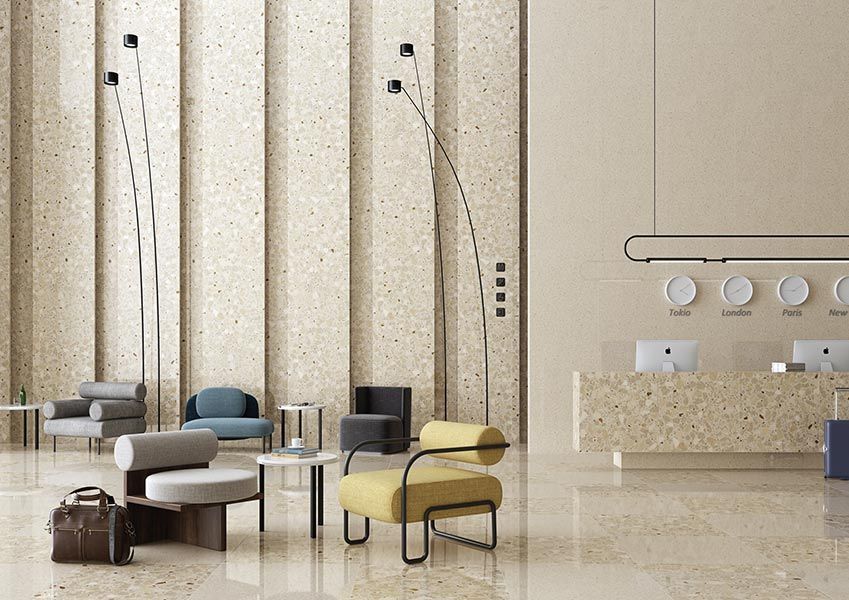 Vestíbulo con suelos y paredes de terrazo, zonas de estar y recepción. Diseño moderno con colores neutros.