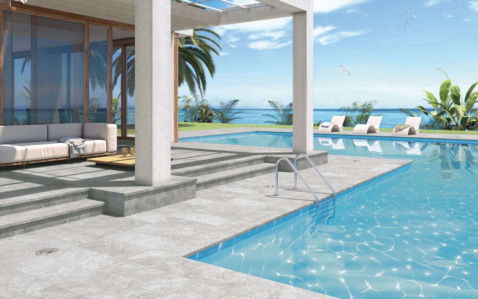 Vista de la piscina de una lujosa villa con piscina, océano y tumbonas en un día soleado.