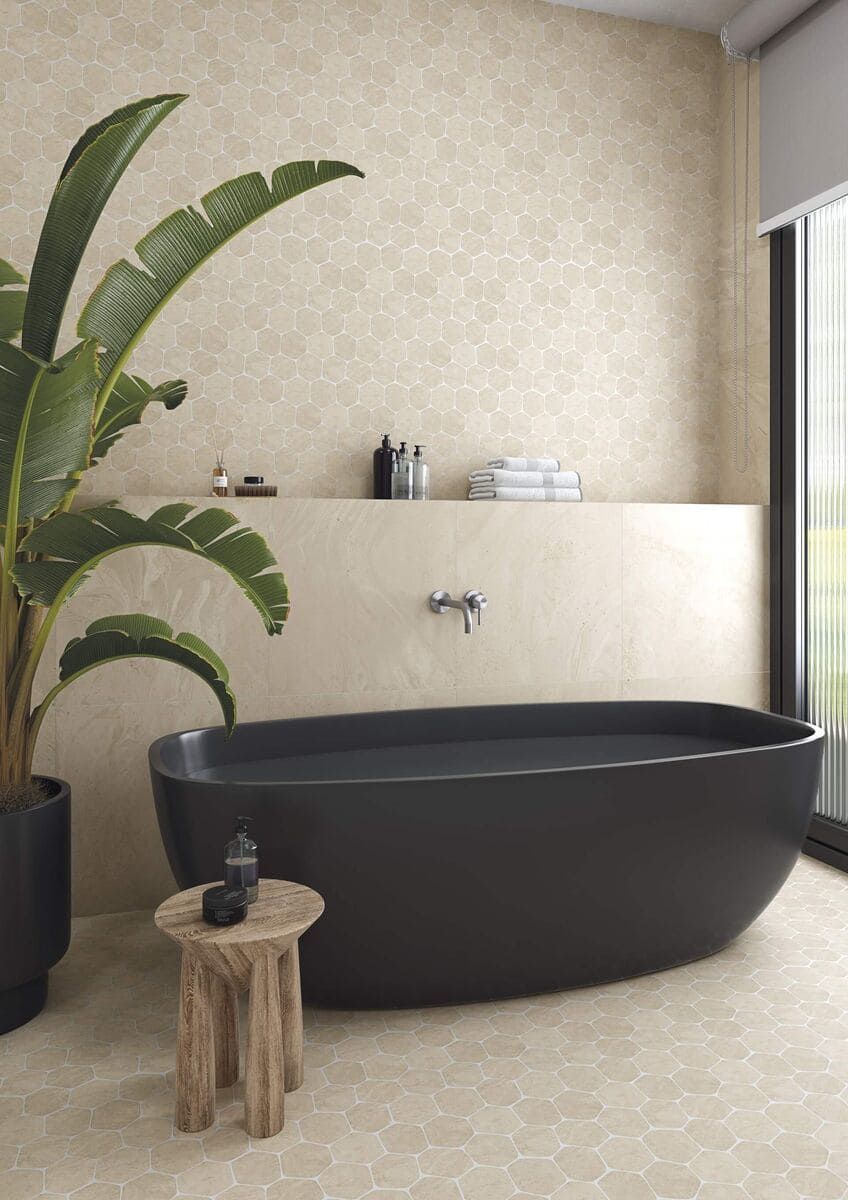 Baño con bañera negra, paredes de color tostado y una planta en maceta.