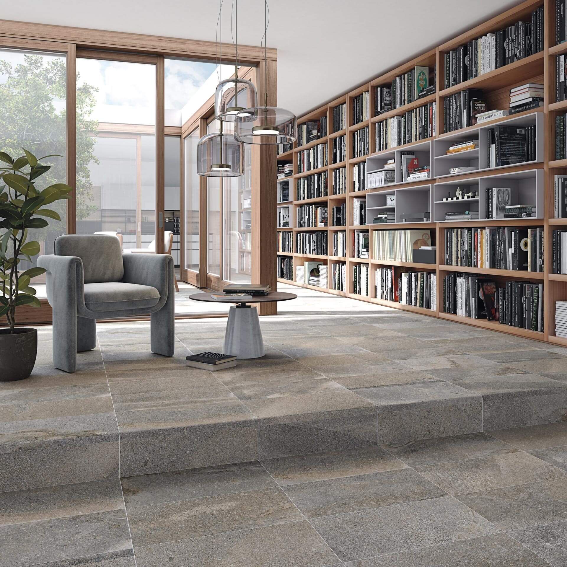 Una biblioteca con estanterías de suelo a techo y una zona de lectura con sillón y mesa.