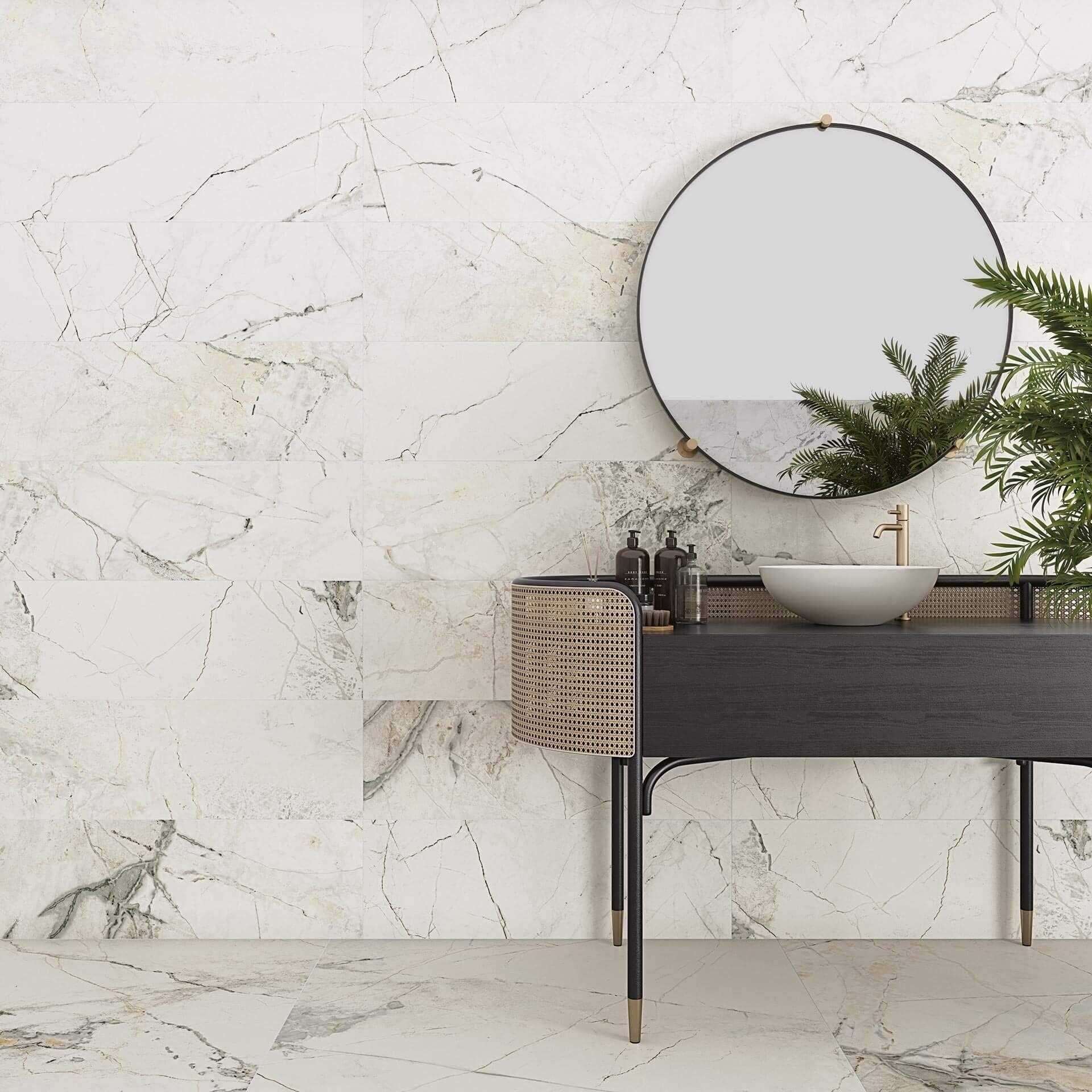 Baño con paredes y suelo de baldosas símil mármol, espejo redondo y tocador oscuro con cesta tejida.
